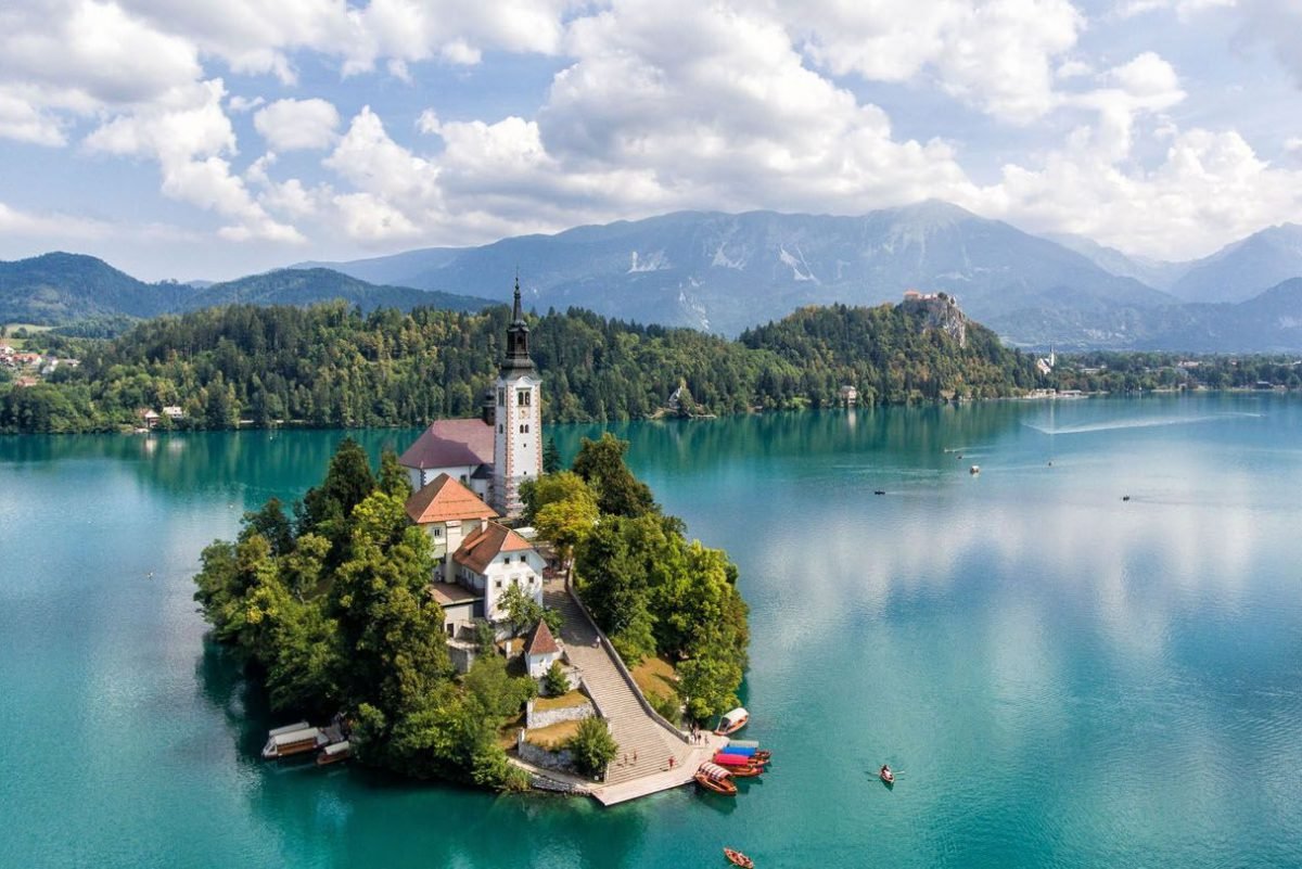Lake Bled, Water, Cloud, Water resources, Sky, Blue, Mountain, Natural landscape, Lake, Coastal and oceanic landforms